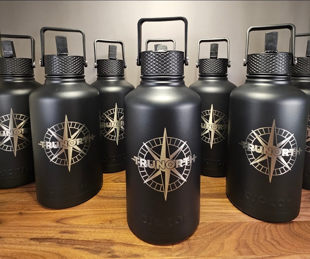 Row of black water bottles with a logo on a wooden surface